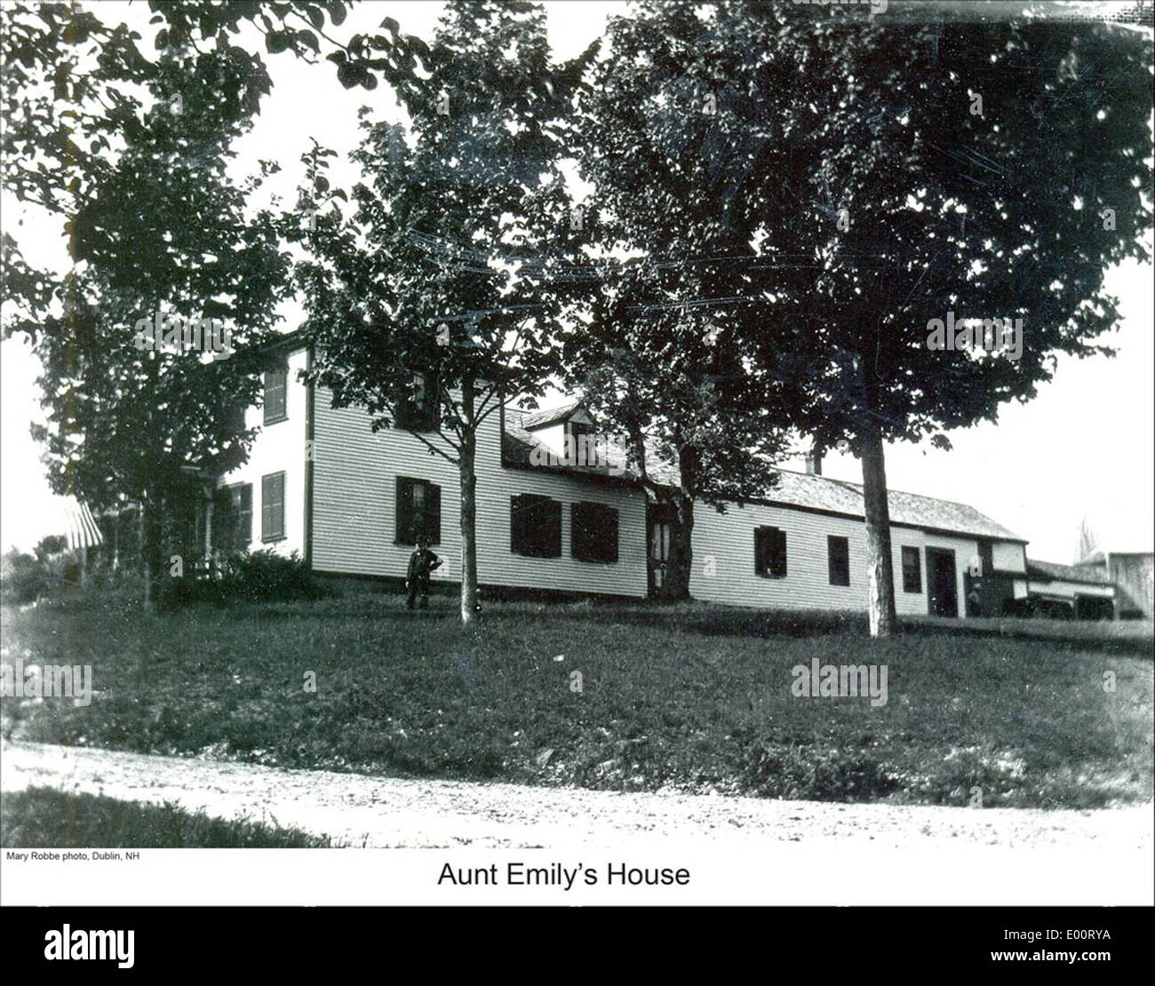 A depiction of Aunt Emily's house in Dublin, New Hampshire, showcasing the New England farmhouse style. The image reflects the peaceful rural setting and charm of the area, with trees surrounding the home in a tranquil environment. Stock Photo