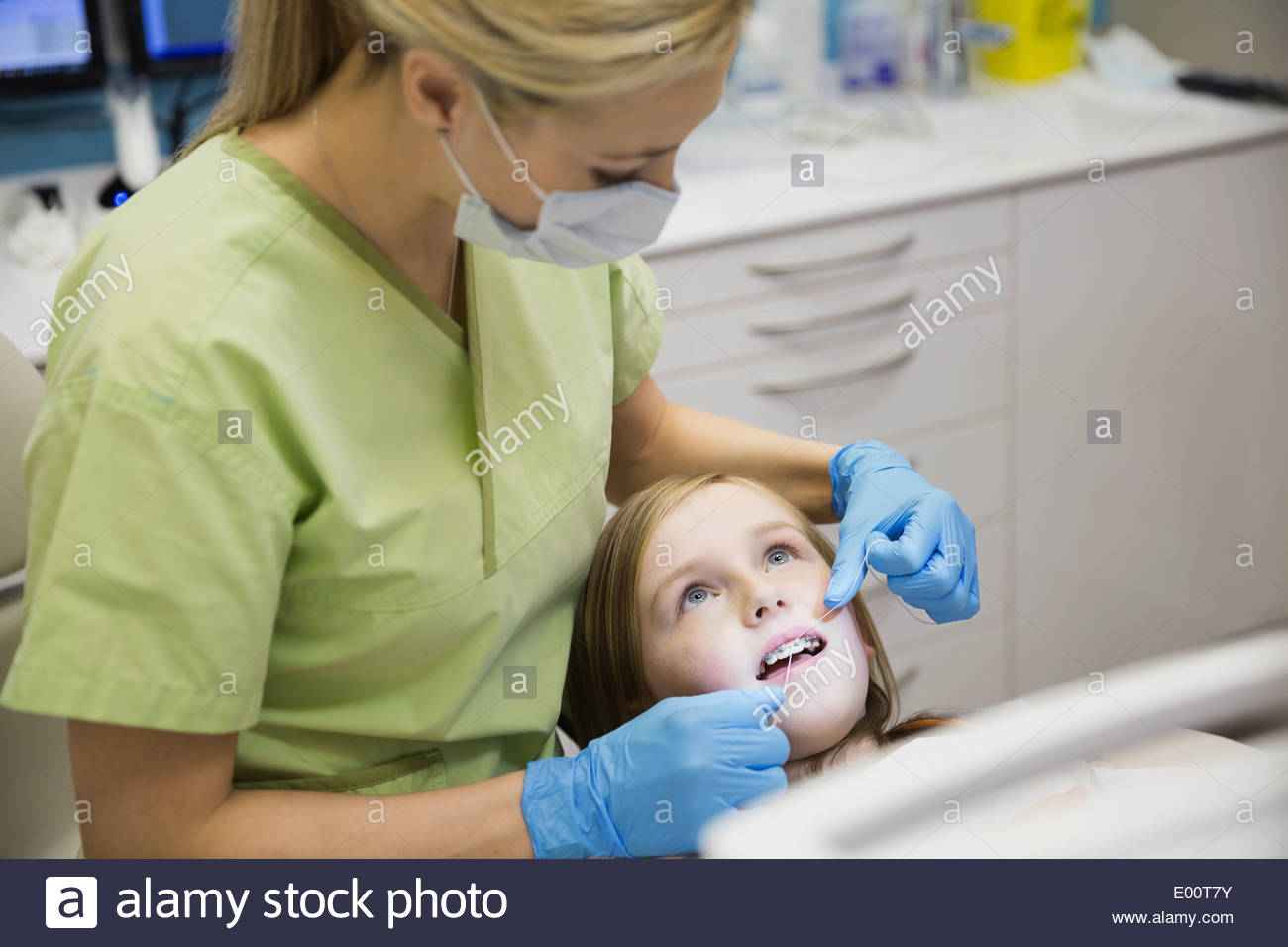 Dental assistant flossing girls teeth Stock Photo