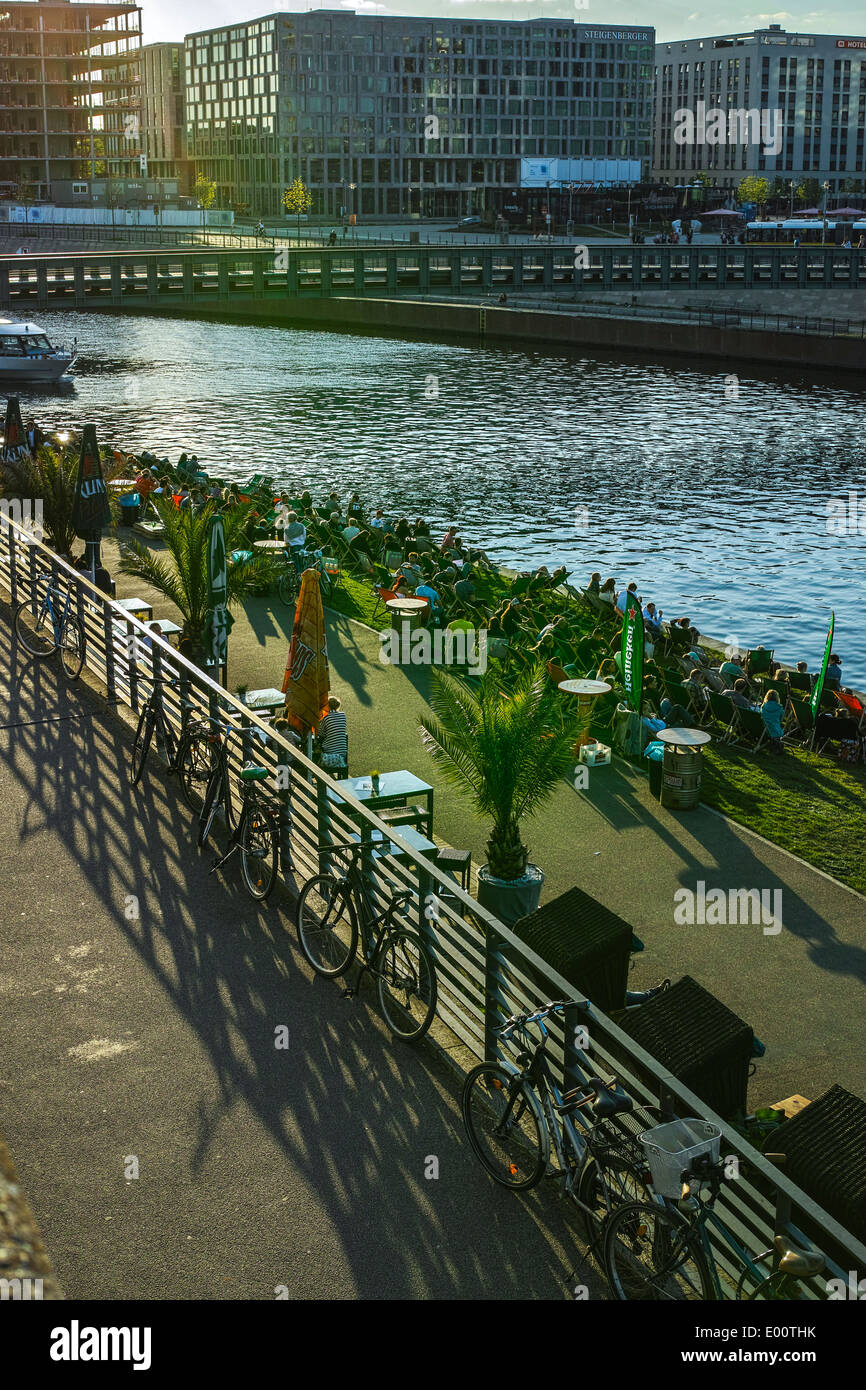 People relaxing in evening sunlight at the Ludwig-Erhard-Ufer in a pub garden. Stock Photo