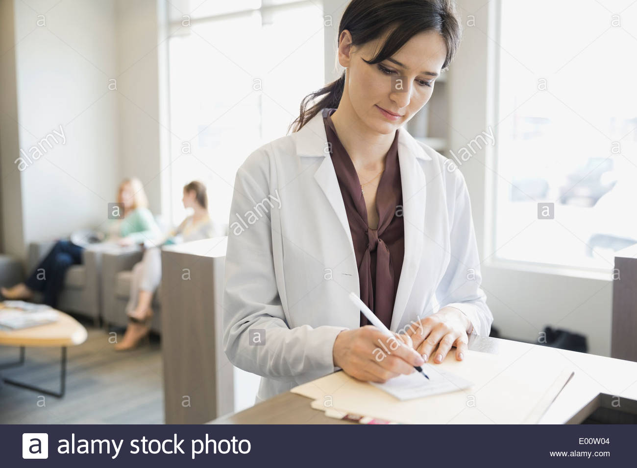 Dentist writing prescription at front desk Stock Photo Alamy