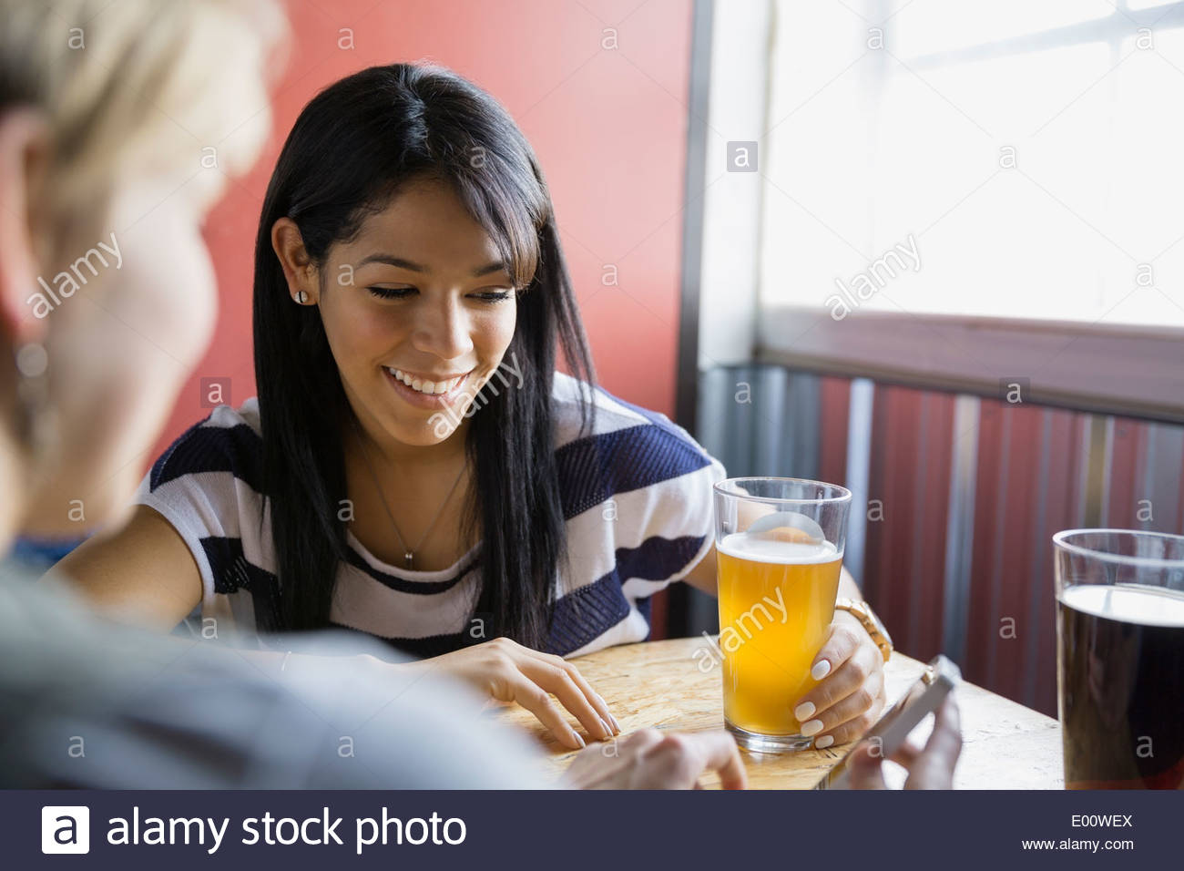 Women text messaging with cell phone at brewery Stock Photo
