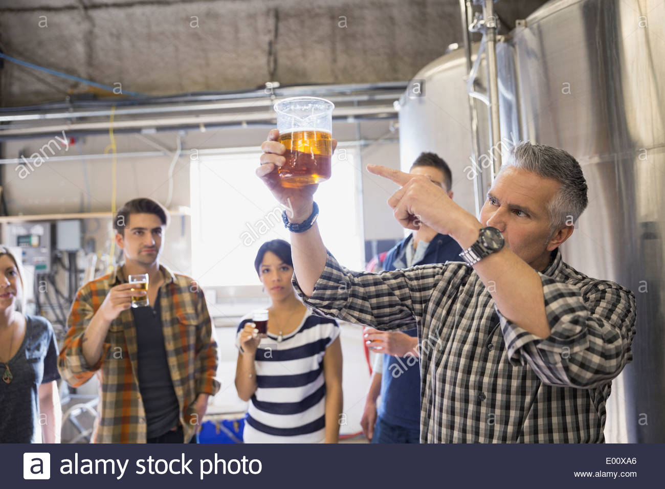 Brewery tour guide pointing to beer in beaker Stock Photo Alamy