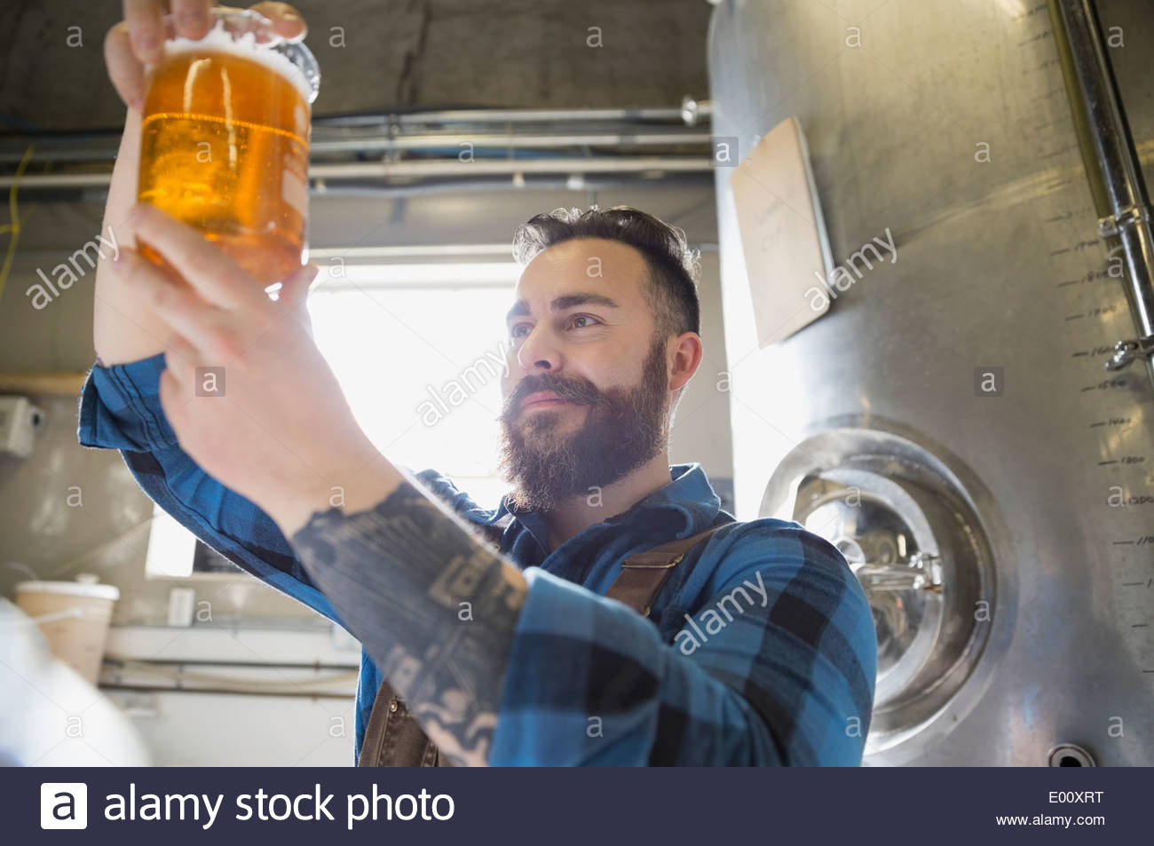 Brewery worker examining beer in beaker Stock Photo