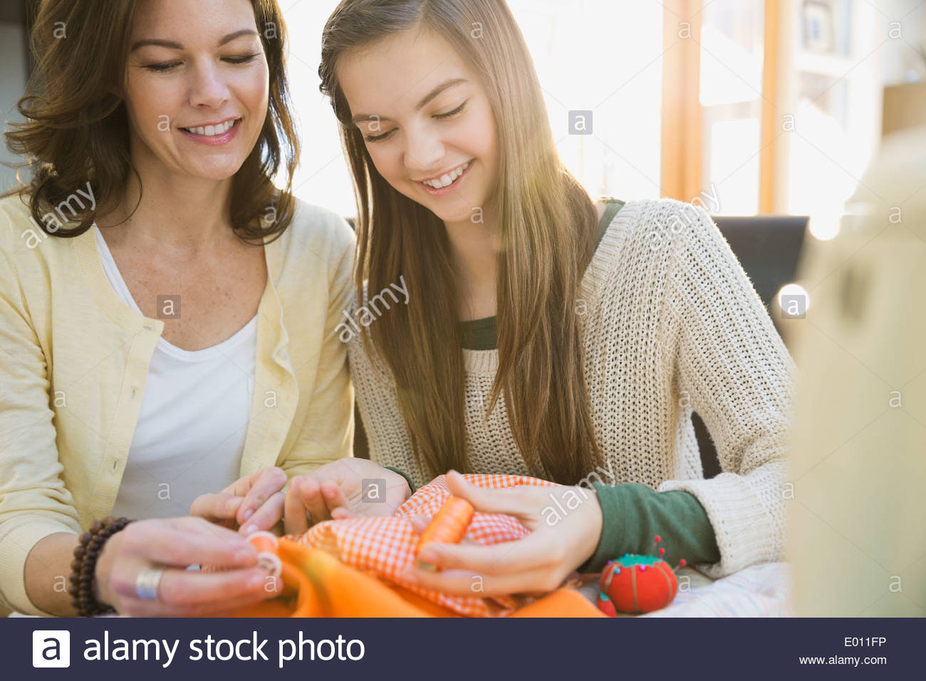 Mother teaching daughter to sew Stock Photo