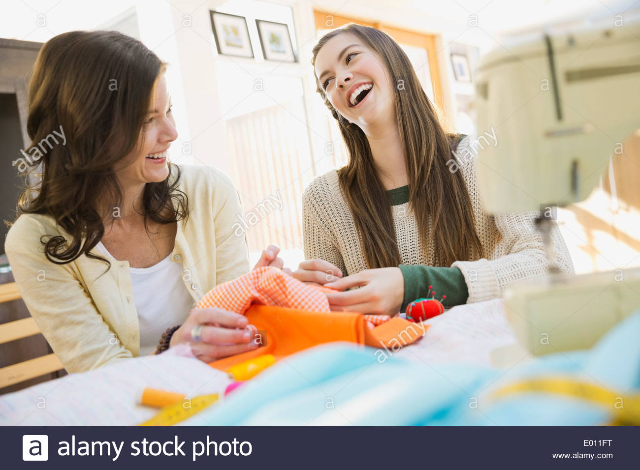 Mother teaching daughter to sew Stock Photo
