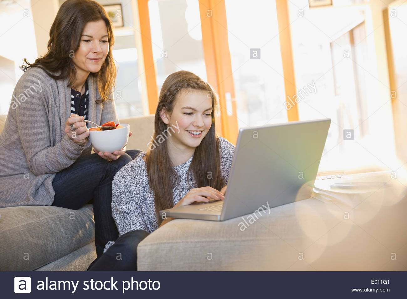 Mother and daughter using laptop in living room Stock Photo - Alamy