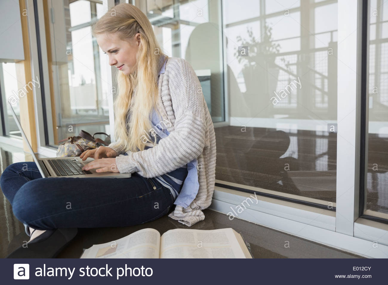 High school student using laptop on floor Stock Photo