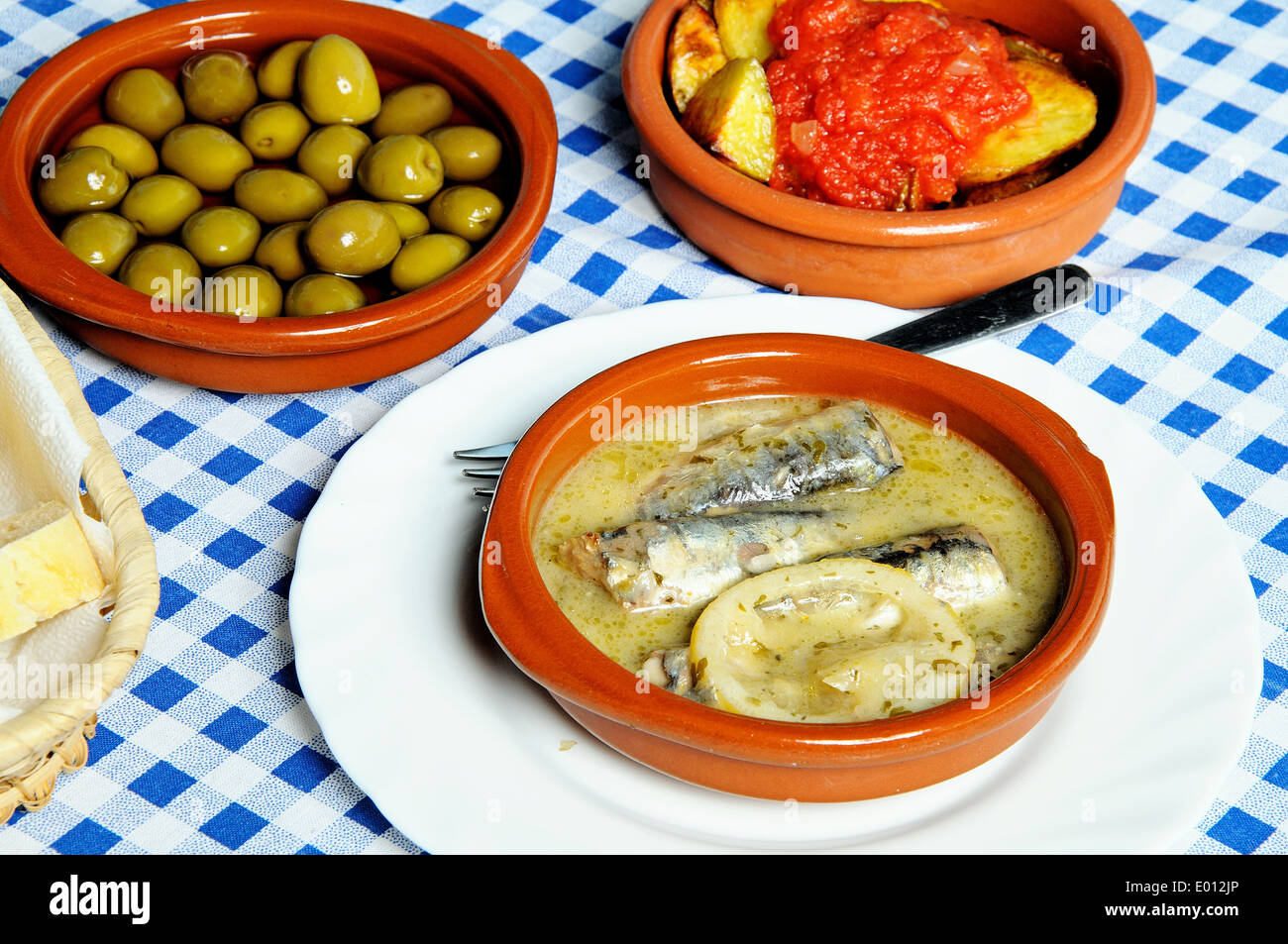 Spanish tapas selection of sardines in lemon sauce, patatas bravas and green olives. Stock Photo