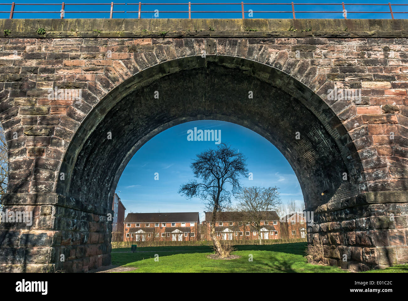 A Victorian railway viaduct frames modern urban housing in the town of Northwich, Cheshire. Stock Photo