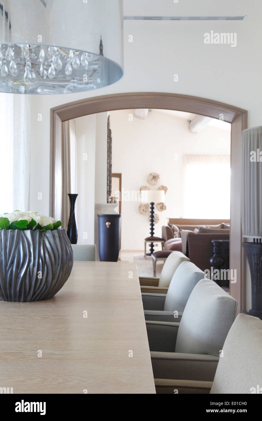 Detail of modern chandelier over dining table and dining chairs in