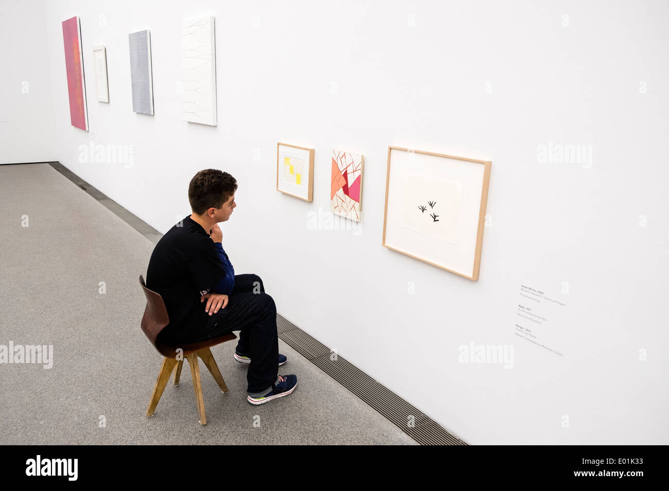 Boy looking at art works on chair provided at low level at Pinakothek Museum in Munich Germany Stock Photo
