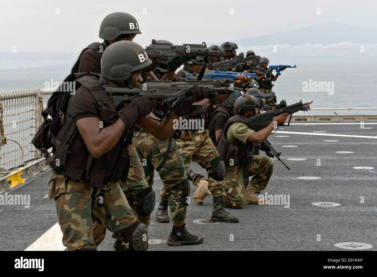 Nigerian sailors with the Special Boat Service and Cameroonian soldiers with the Rapid Intervention Battalion secure the flight deck during a simulated boarding scenario aboard the joint high speed vessel USNS Spearhead during Obangame Express joint training with US Navy SEAL team members April 20, 2014 in the Gulf of Guinea. Stock Photo
