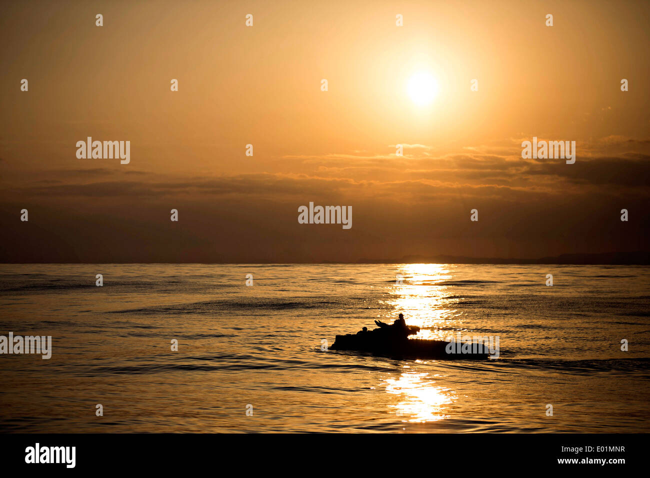 A US Marine Corps amphibious assault vehicle maneuvers through the water at sunset during a splash and recovery exercise February 28, 2014 in the East China Sea. Stock Photo