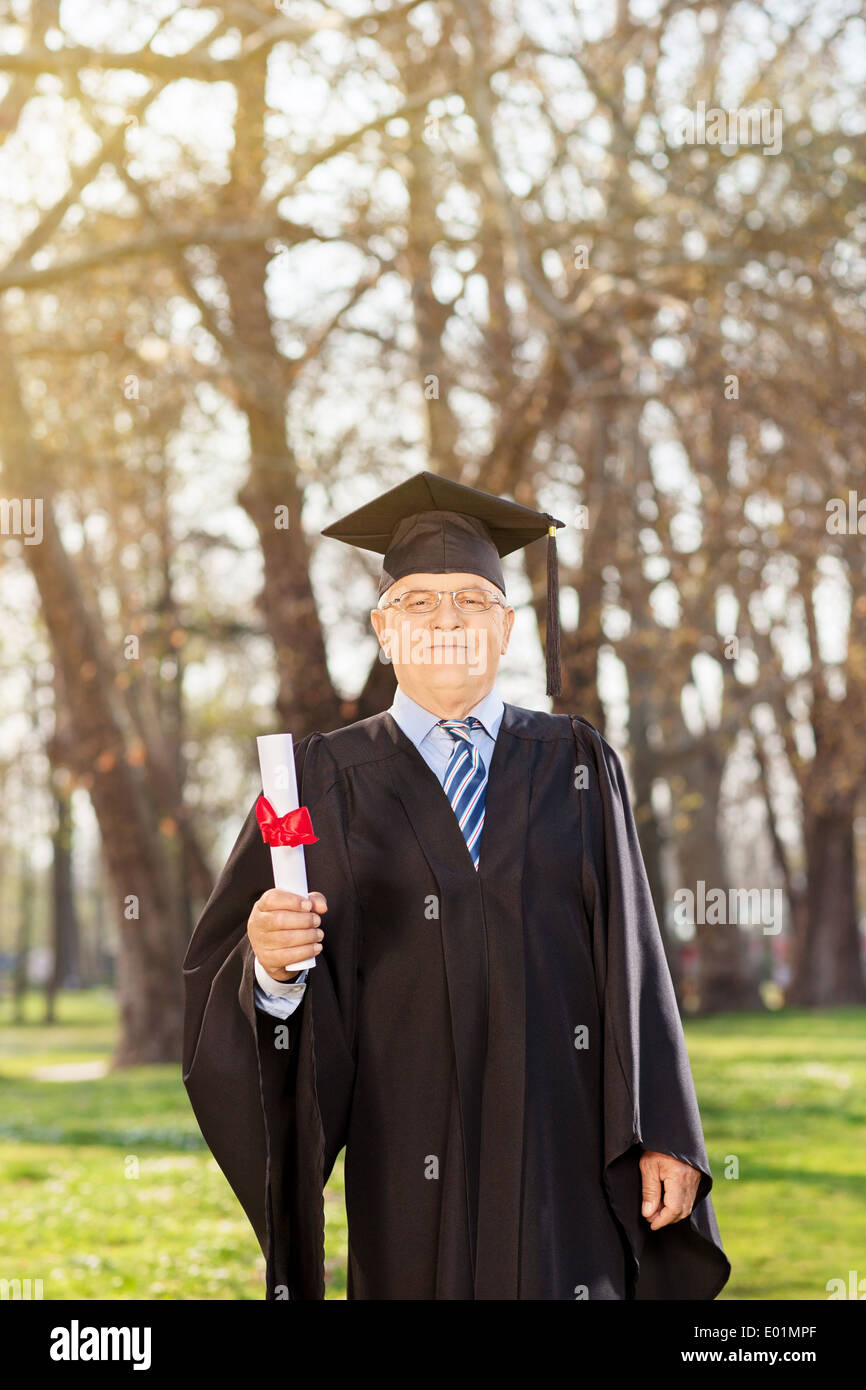 Mature man posing with a diploma in park Stock Photo