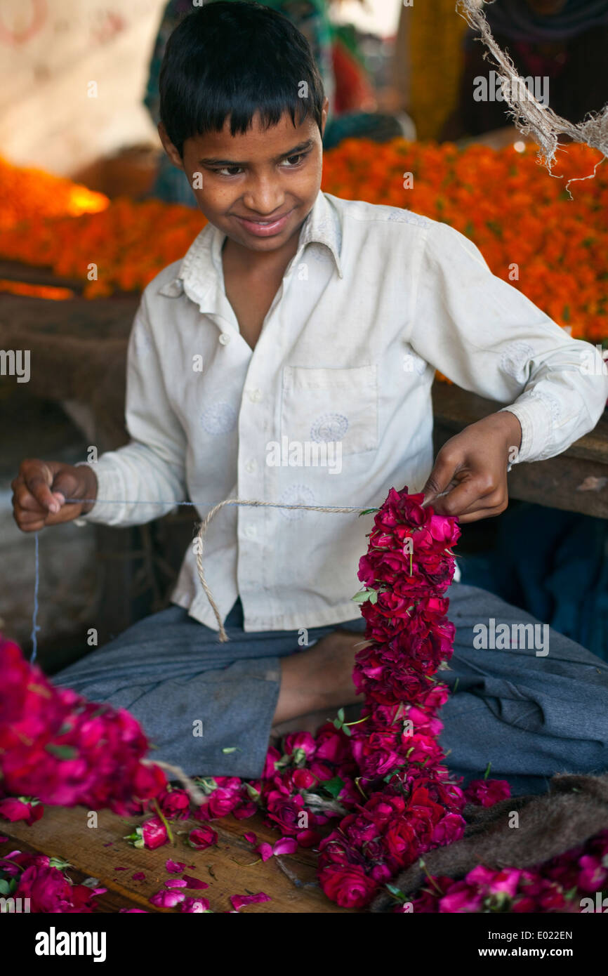 A boy threads marigolds for a garland at the Mehrauli flower market, Delhi, India Stock Photo