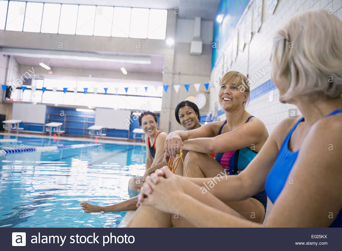 Women talking at indoor swimming pool Stock Photo