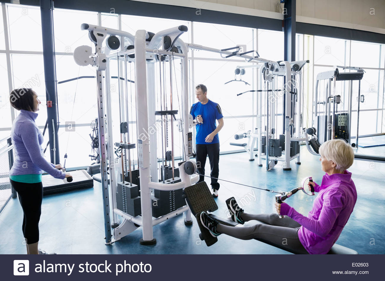 People using weight machines at gym Stock Photo