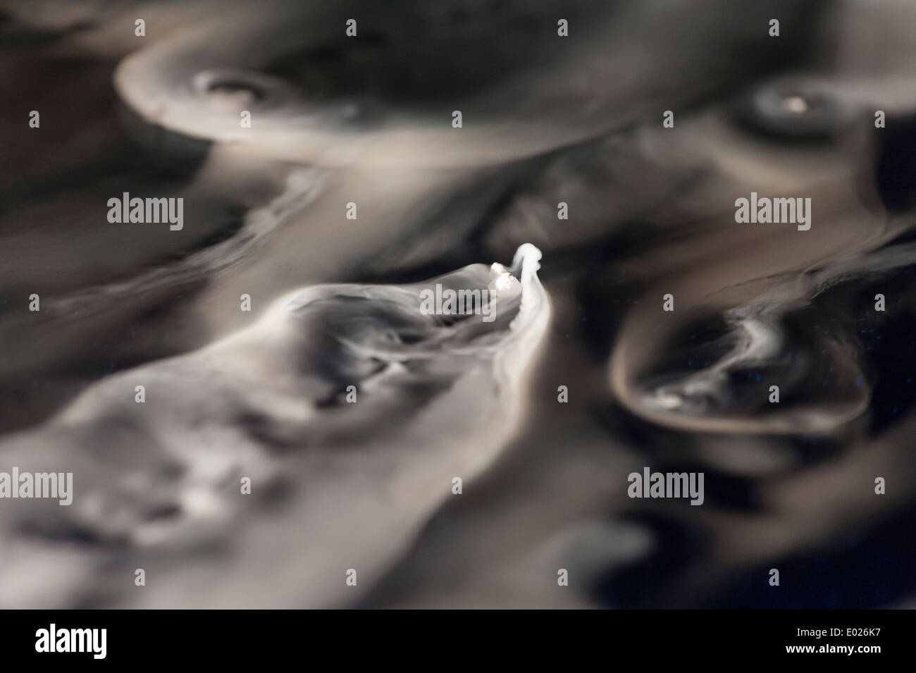 A small (1cm large) piece of solid frozen carbon dioxide snow is floating on a water surface while it is evaporating. Stock Photo