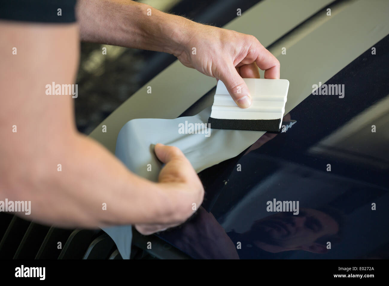 Car wrapper straightening wrapping foil with a squeegee to remove air