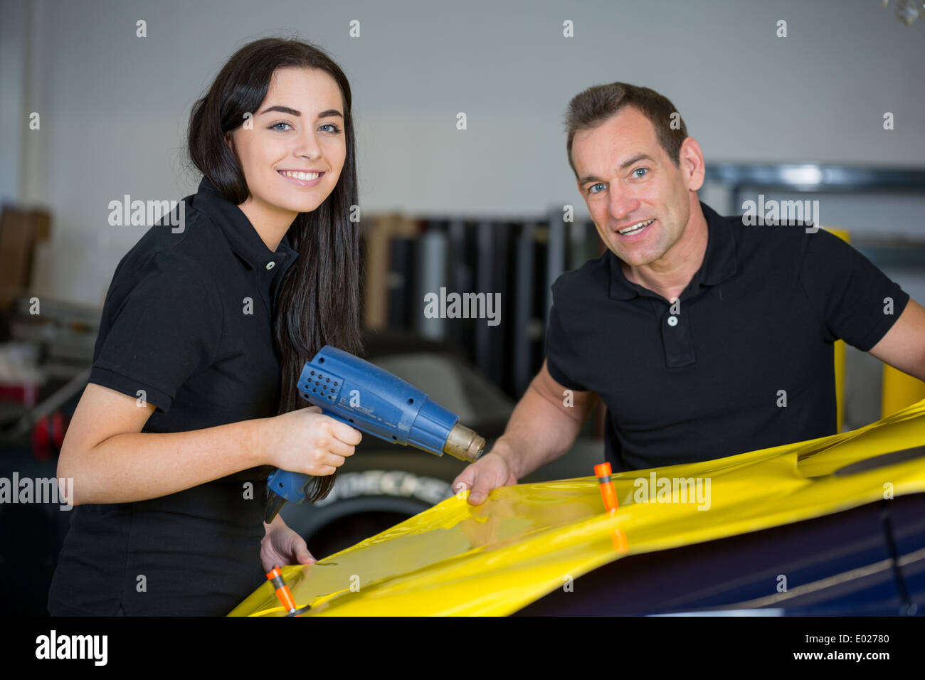 Car wrapping specialists using heat gun to prepare vinyl foil Stock