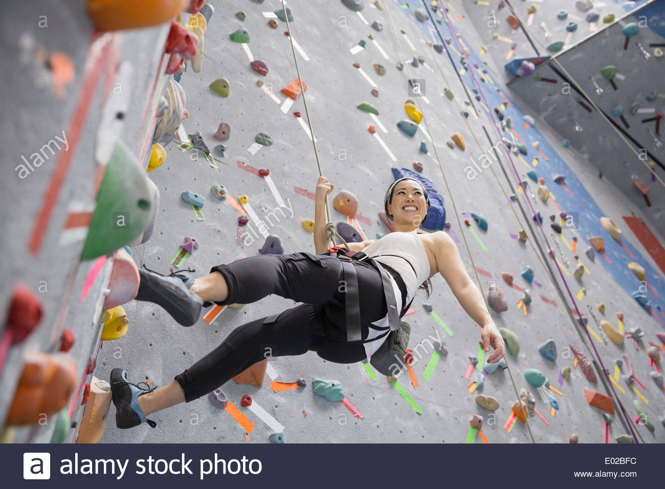 Smiling woman climbing indoor rock wall Stock Photo