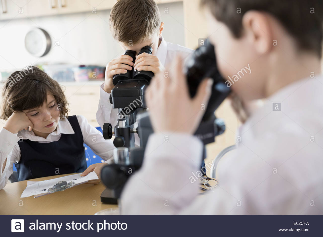 Elementary students using microscopes in science classroom Stock Photo