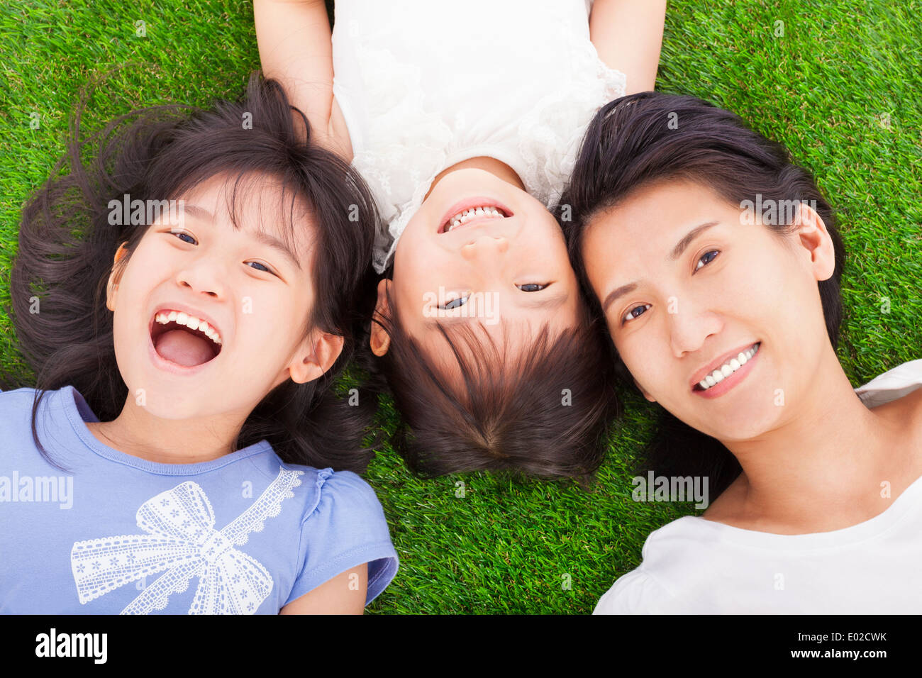 happy mother and daughters lying on a meadow Stock Photo