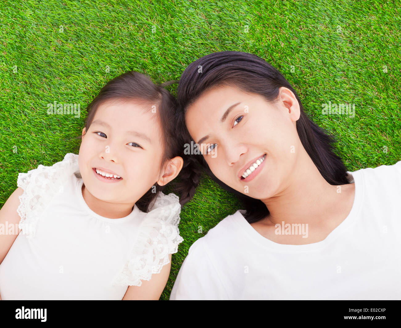 smiling mother and daughter lying on a meadow Stock Photo