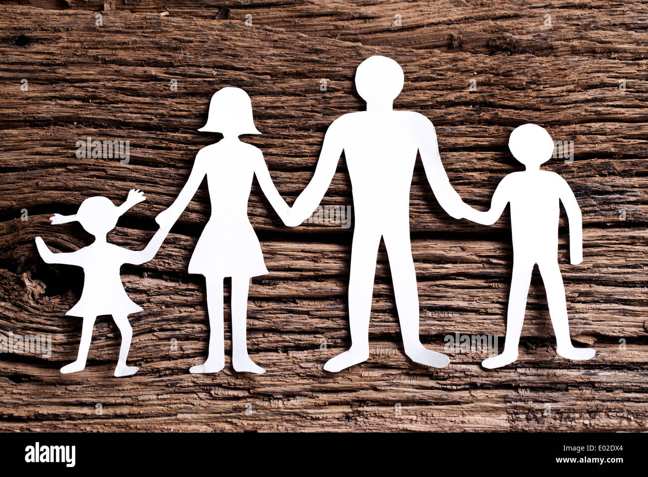 Cardboard figures of the family on a wooden table. The symbol of unity and happiness. Stock Photo