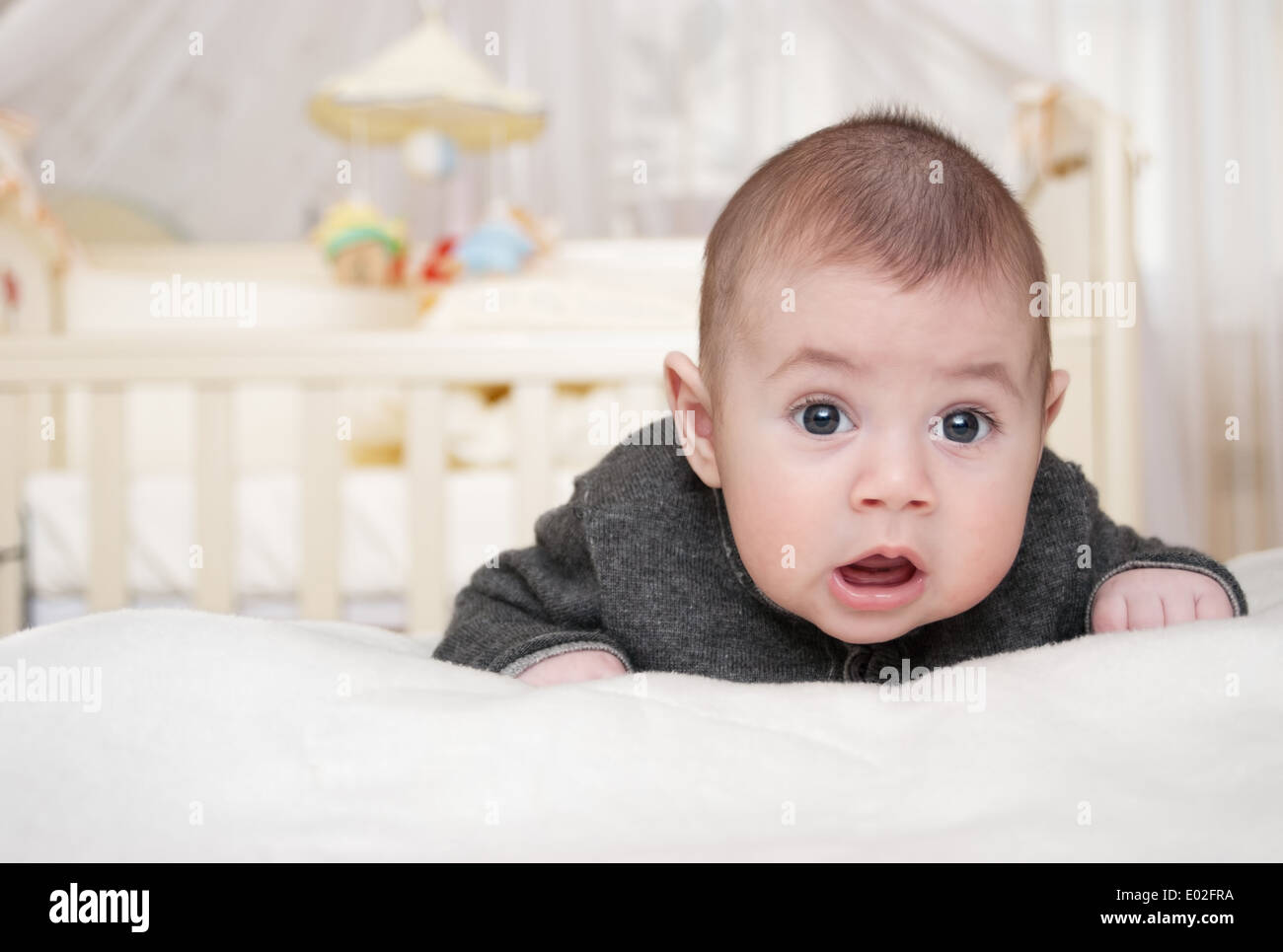 little toothless baby lies on a stomach and with astonishment looks