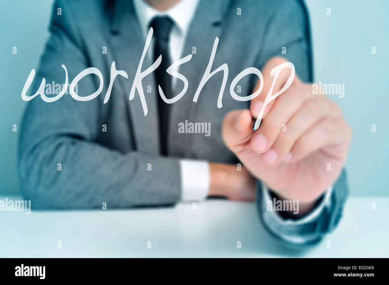 man wearing sitting in a desk writing the word workshop in the foreground Stock Photo