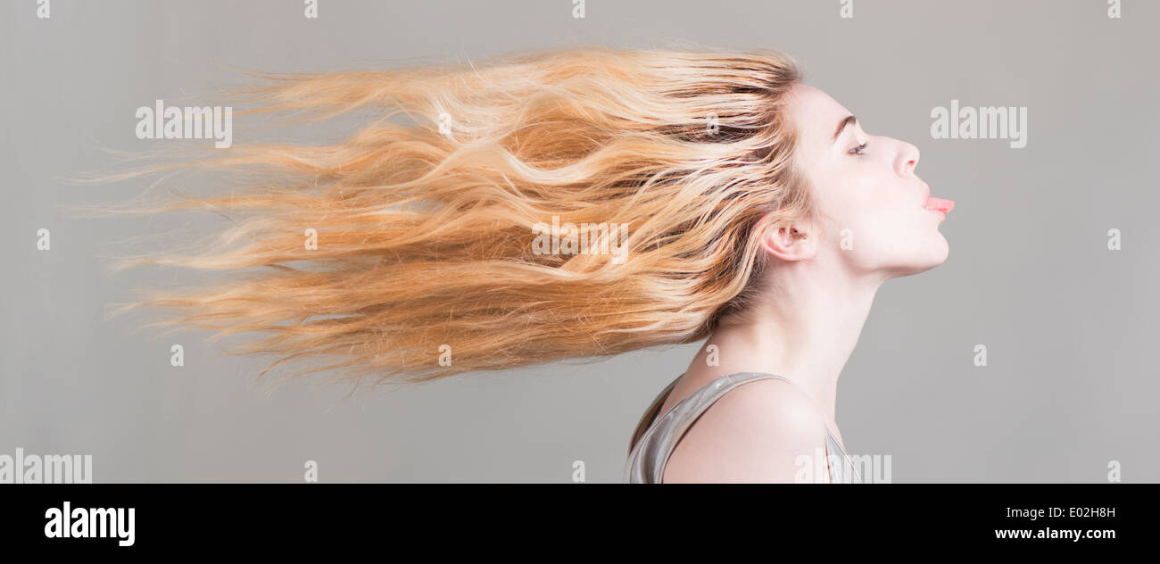 Blonde woman with long hair flying sticking her tongue out. Conceptual image of freedom, strong attitude and personality. Stock Photo