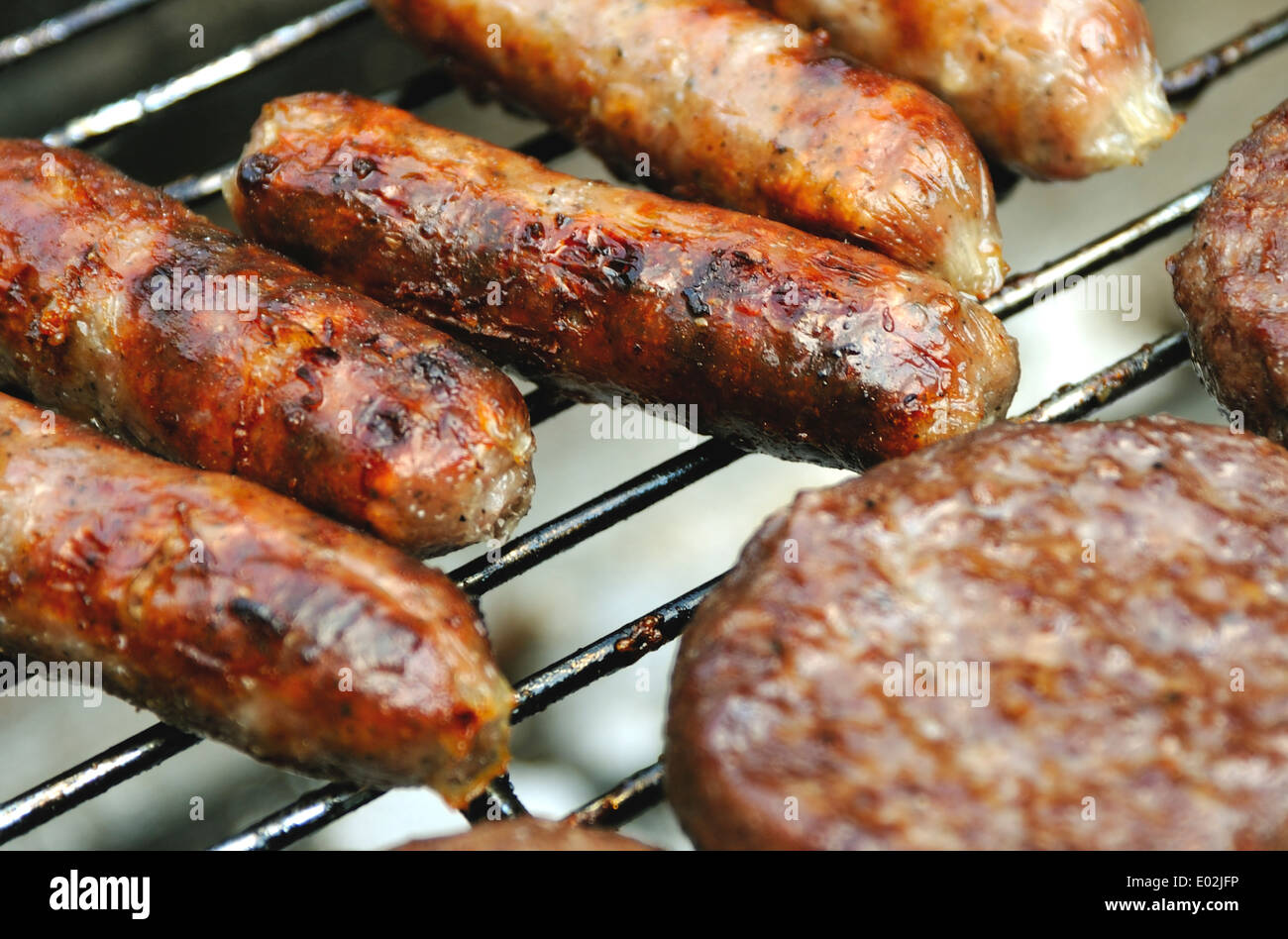 SAUSAGES  AND HAM BURGERS ON A  BBQ Stock Photo