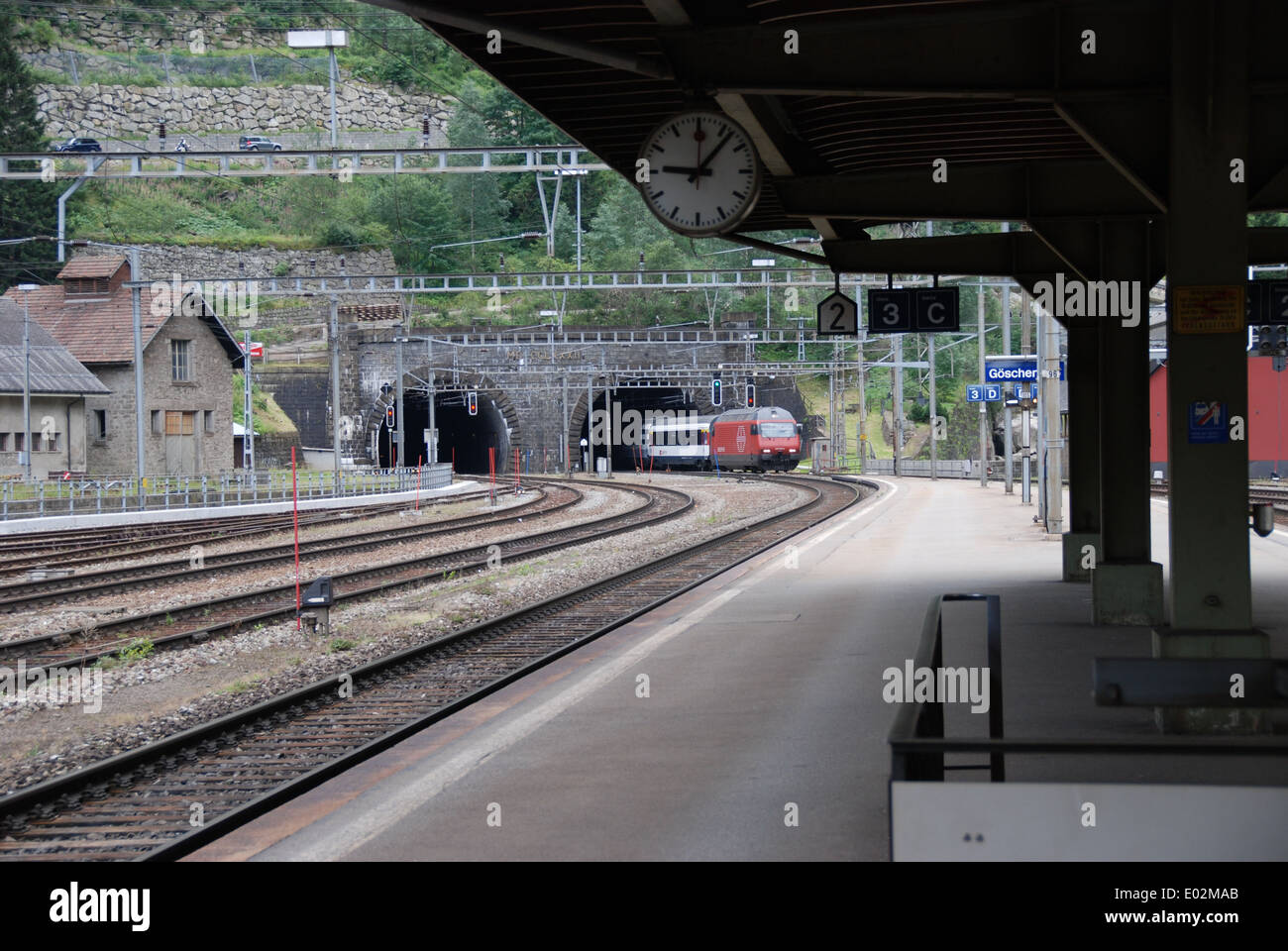 Goschenen railway station in Switzerland looking towards northern entrance of St. Gotthard Tunnel with train emerging. Stock Photo