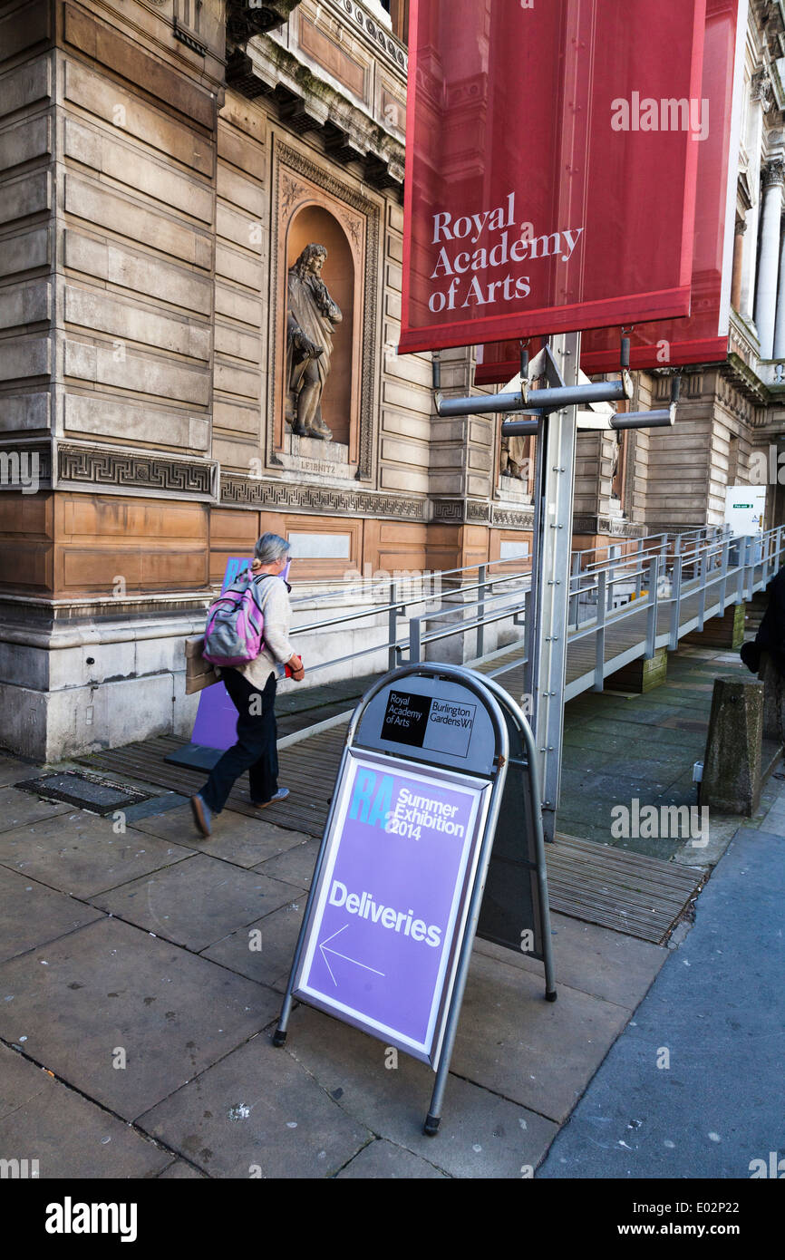 Woman carrying painting entering Royal Academy Summer Exhibition submission entrance. Stock Photo