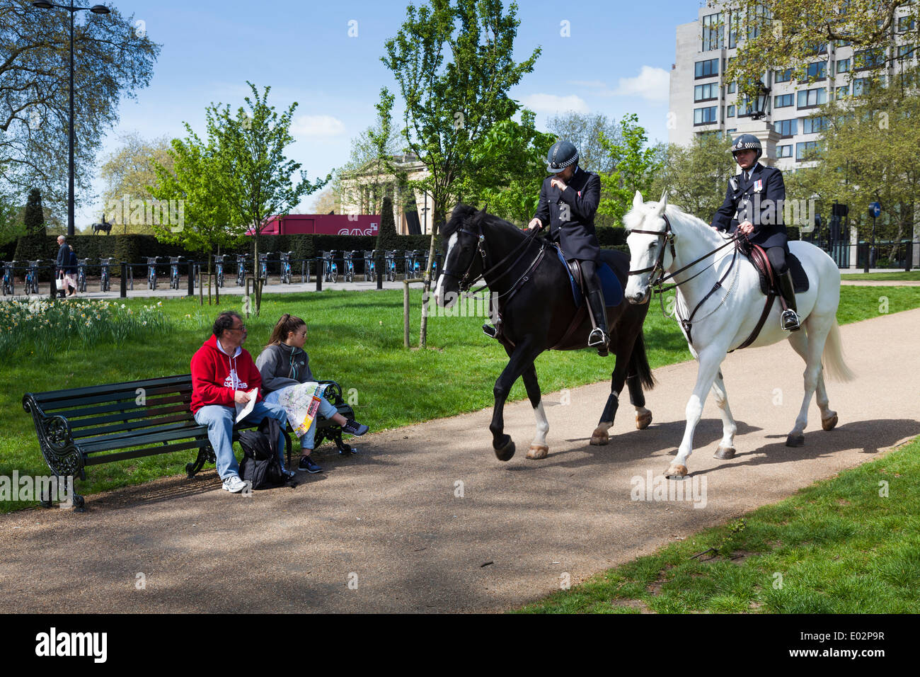 Two metropolitan mounted police riding through Green Park London. Stock Photo