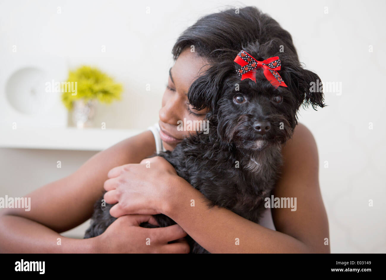 A young girl hugging her small black pet dog. Stock Photo