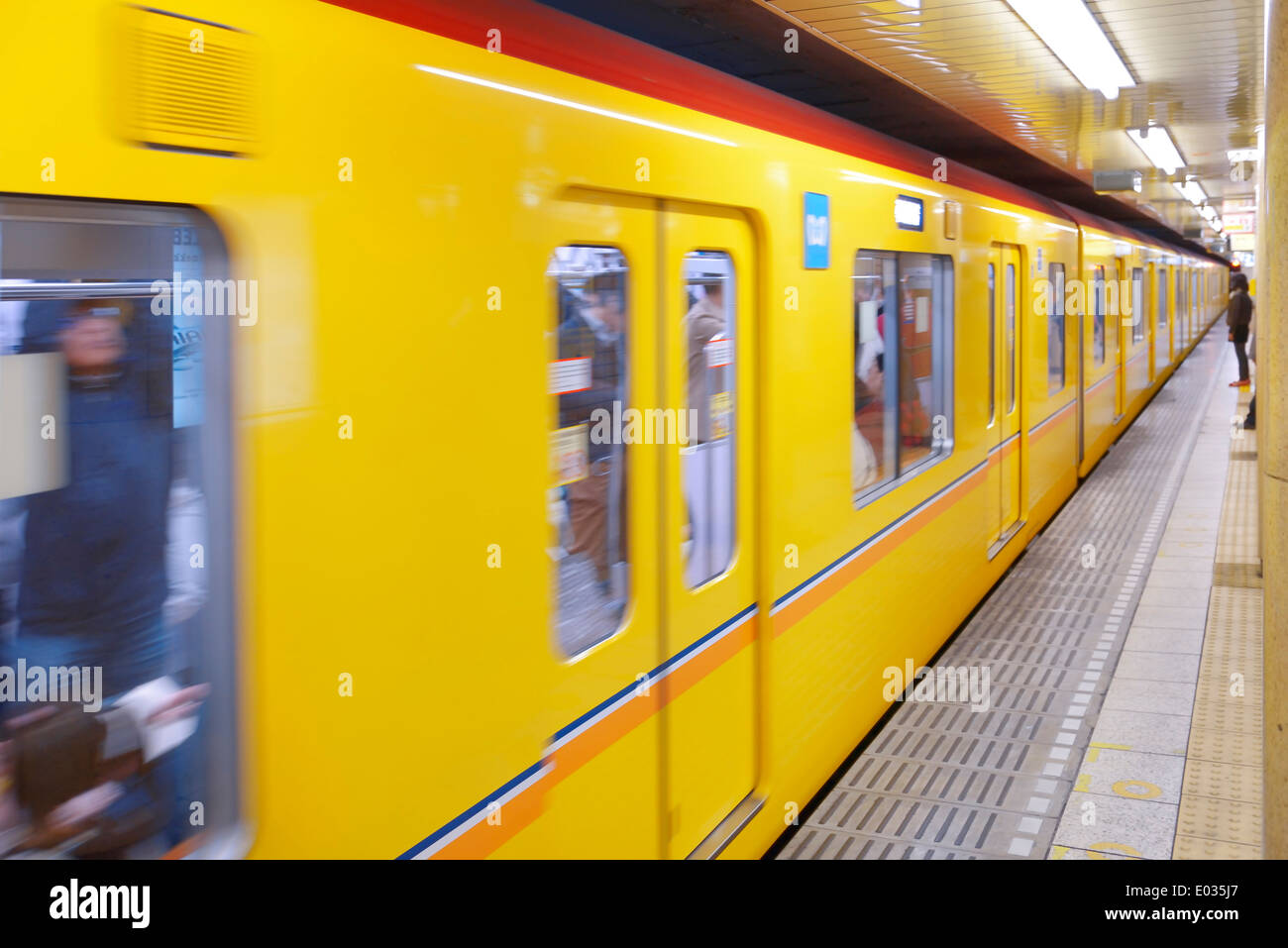 Tokyo Metro yellow subway train arriving to a subway station platform. Tokyo, Japan. Stock Photo