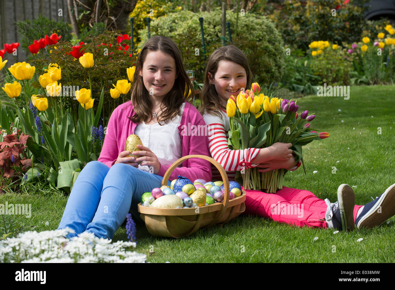 Easter egg hunt girls with their chocolate eggs and Spring flowers Stock Photo
