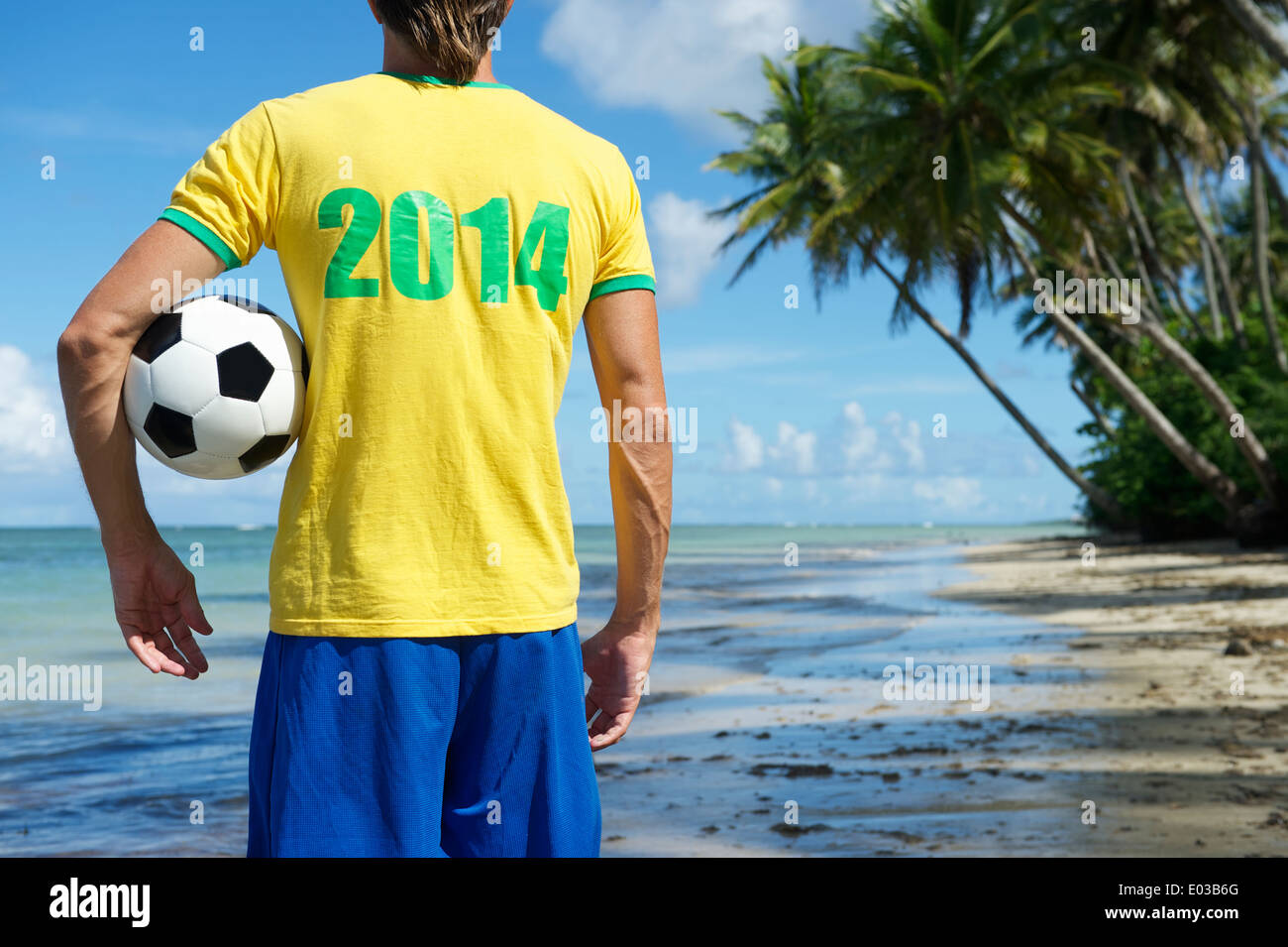 Brazilian football player in 2014 shirt holding soccer ball on remote beach in Nordeste Bahia Brazil Stock Photo