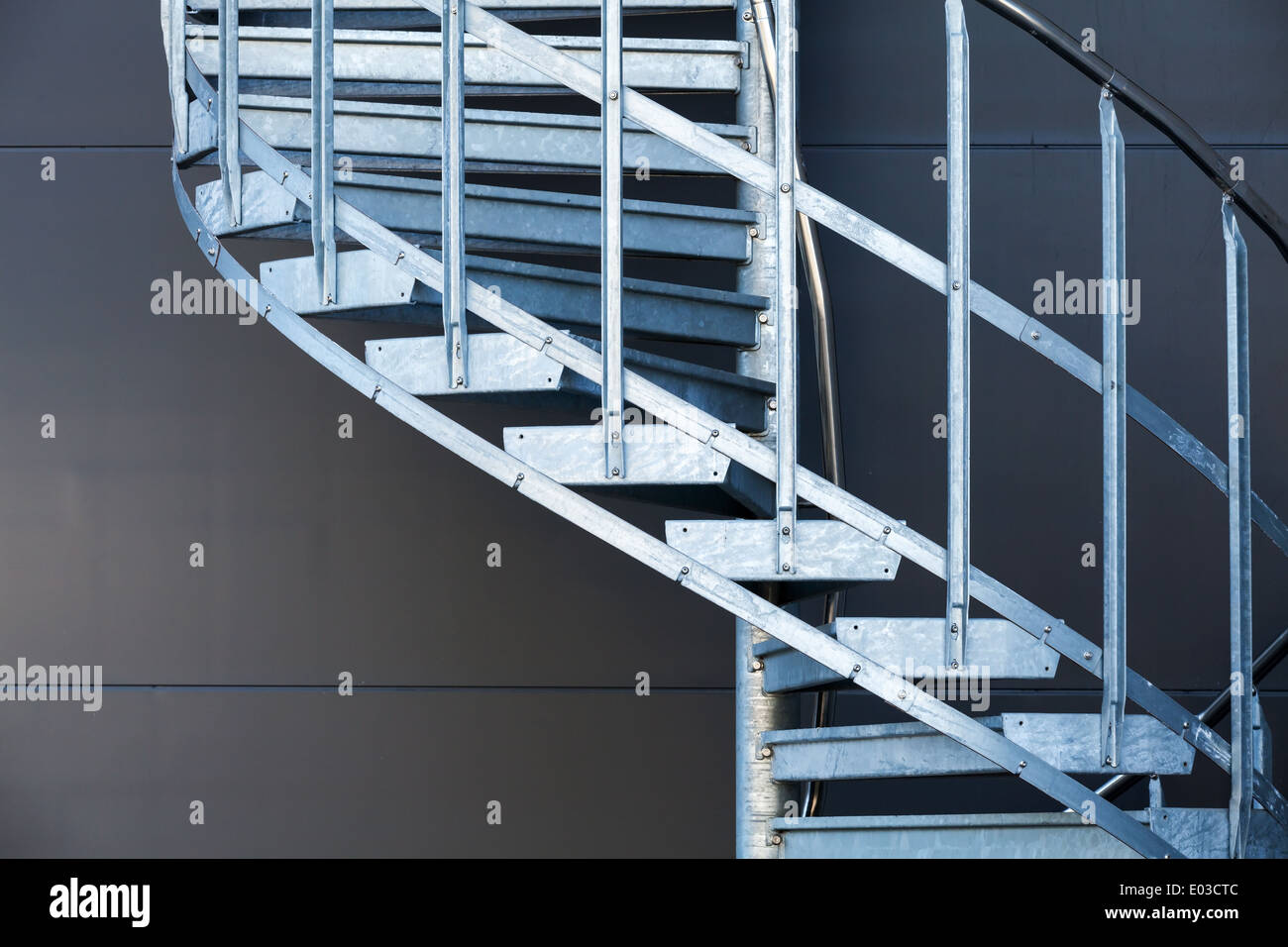 Fragmetn of modern metal spiral staircase above dark gray wall Stock Photo