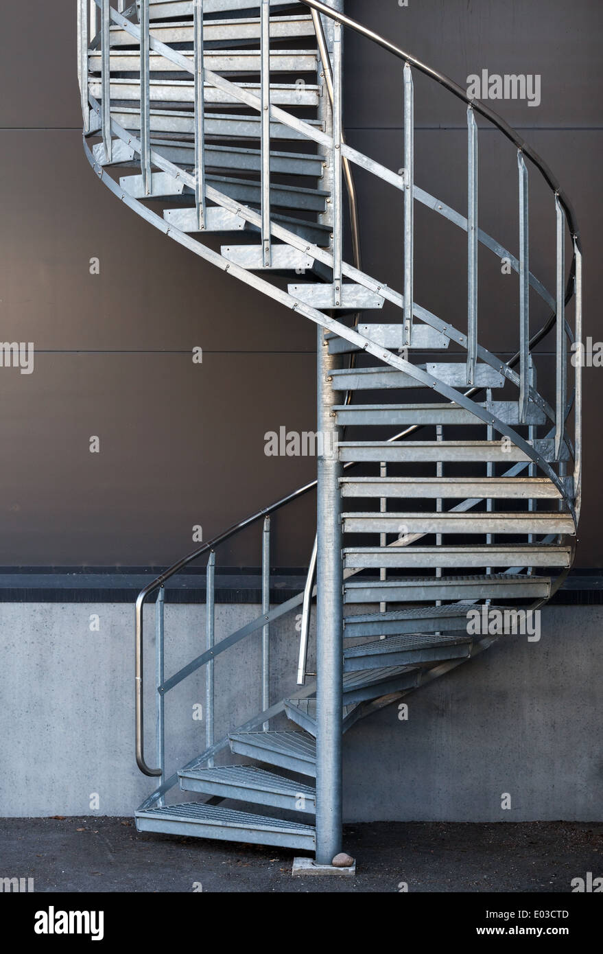 Modern metal spiral staircase above dark gray wall Stock Photo