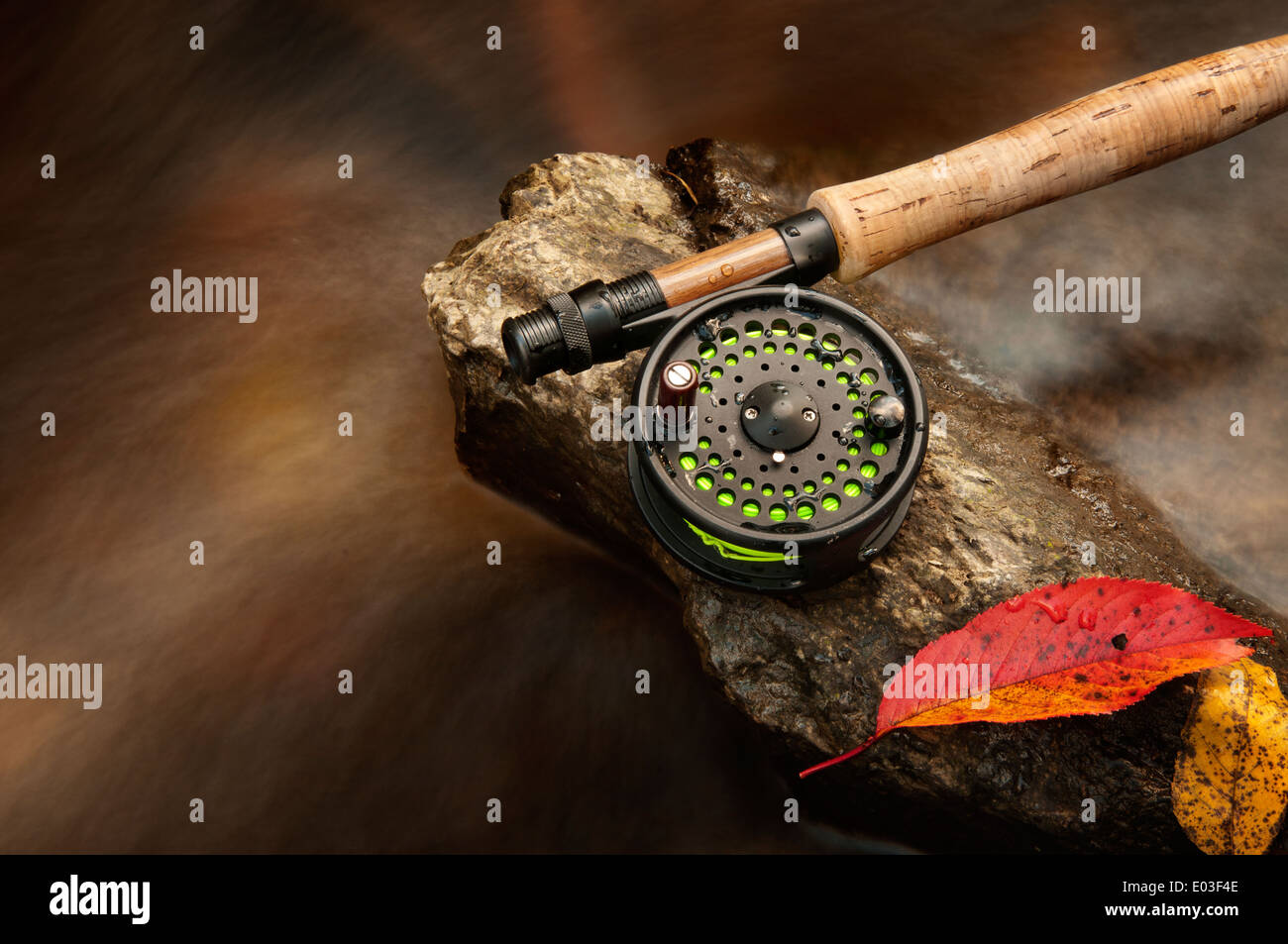 Fly rod resting on a rock in a creek during the autumn Stock Photo