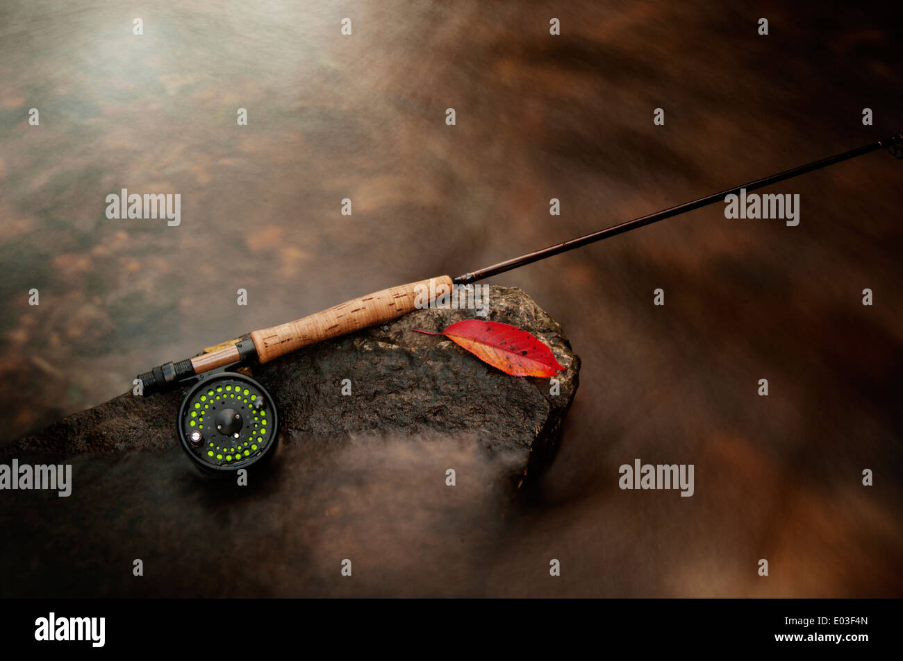 Fly rod resting on a rock in a creek during the autumn Stock Photo