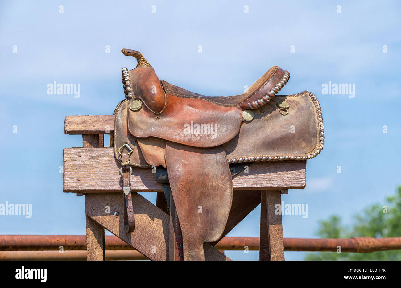 Leather horse saddle displayed on a stand against blue sky Stock Photo