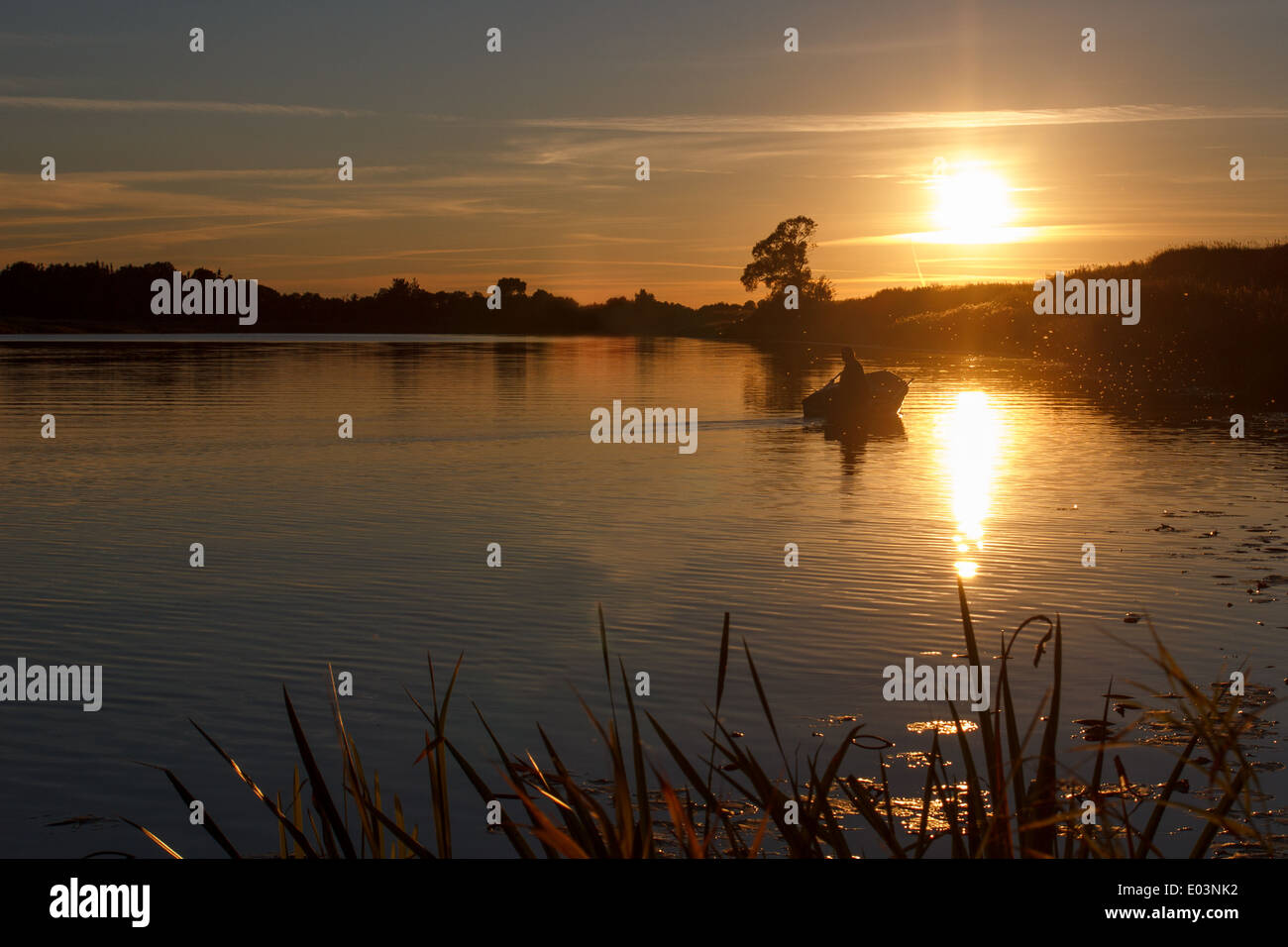 Sunset on the river. A lone fisherman in a boat Stock Photo - Alamy