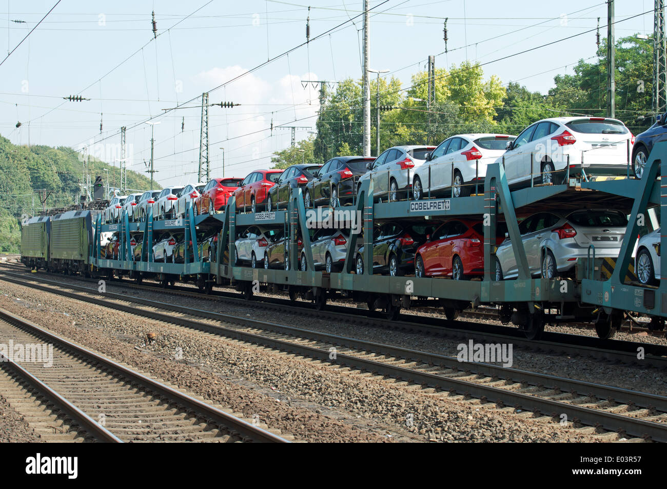 Cobelfret rail car transporter loaded with Ford cars running through Cologne Germany Stock Photo