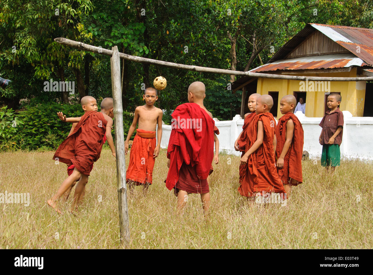 Buddhist novices are playing takraw in front of a temple. Stock Photo