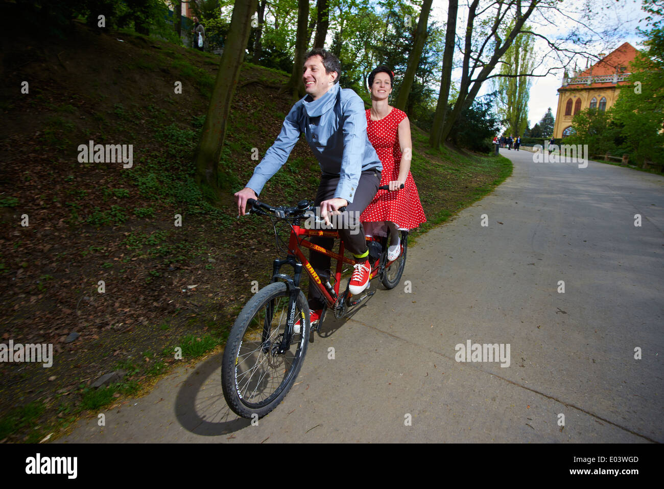 Couple young man and woman riding a tandem bicycle, cycling in the park Stock Photo