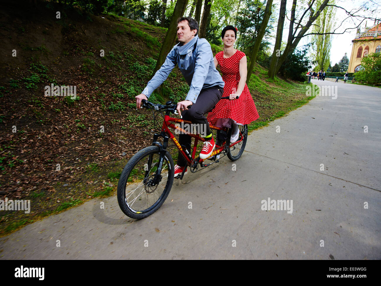 Couple young man and woman riding a tandem bicycle, cycling in park Stock Photo
